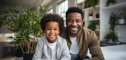 Portrait of father and son. African american middle age male with boy, smiling and happy sitting indoor. Father's Day concept.