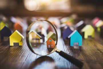 Real estate market analysis concept with cardboard houses and a magnifying glass focusing on a single home, symbolizing property evaluation - AI generated - obrazy, fototapety, plakaty