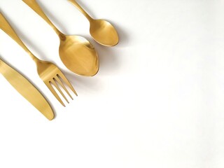 Gold cutlery, knife, fork, spoon isolated on a white background with copy space 