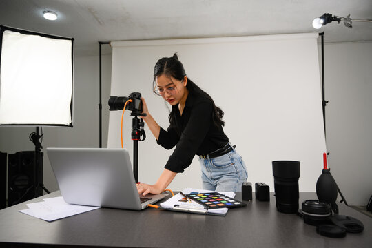 Portrait of female photographer with professional camera working in modern studio