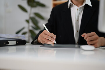Unrecognizable businessman signing contract or writing important notes on digital tablet