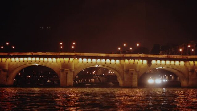 Low angle view from water of Port Neuf bridge illuminated at night in Paris