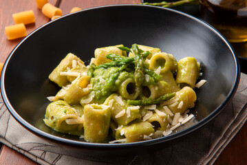 Piatto di deliziosi rigatoni conditi con salsa di asparagi selvatici e parmigiano, pasta italiana vegetariana 