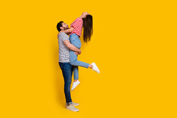 Full size photo of couple dressed striped t-shirt guy hold girlfriend look up at empty space offer isolated on yellow color background