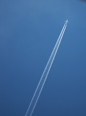 An airplane with a contrail is flying in the blue sky - 764648748