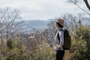 山の上から景色を眺めるハイカーの女性