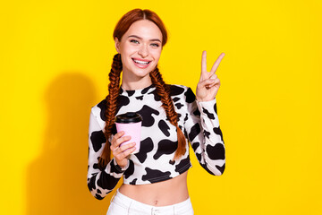 Photo of good mood funky lady dressed cowskin print top showing v-sign enjoying tea isolated yellow color background - 764658969