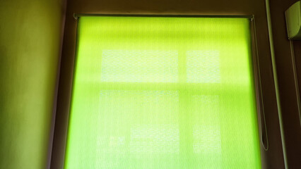 Green Window Shade Casts a Soft Glow in a Dimly Lit Room at Dawn. Background, texture, place for text, copy space