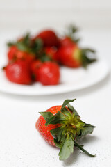Juicy red strawberries lie on a white saucer
