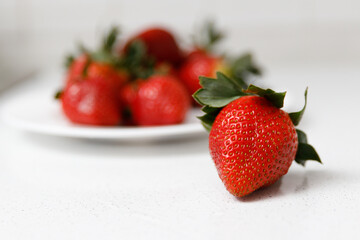 Juicy red strawberries lie on a white saucer