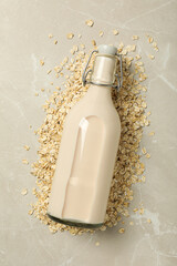 Bottle with milk and oatmeal on beige background, top view