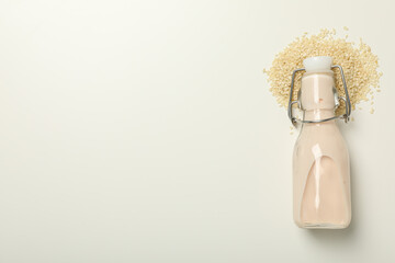 Bottle with milk and sesame seeds on white background, space for text