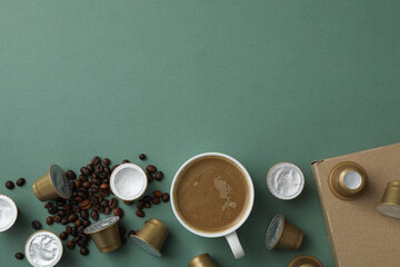 Obraz na płótnie Canvas Coffee capsules, beans, cup with coffee drink and box on green background, space for text