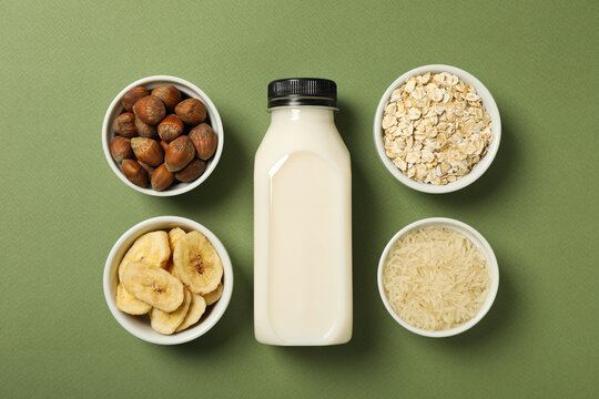 Bottle of alternative milk and herbal ingredients on green background, top view