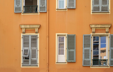 France. Cannes. Beautiful wooden windows with shutters. Beautiful wooden window shutters with window sill, orange cement wall on a sunny day