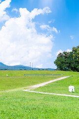 Winding path through a green grass field in hilly area  against blue sky with clouds,Pathway s curve in public park.