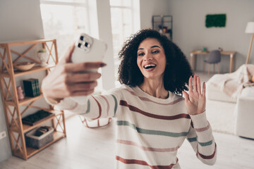 Photo of sweet excited lady dressed striped pullover recording video modern device waving arm hi indoors apartment room - obrazy, fototapety, plakaty