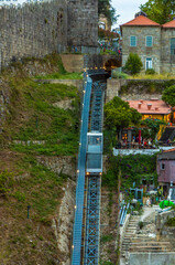 Aerial view of the Guindais Funicular going up the rails of the hill with its picturesque houses and tourists sitting on the terrace of a bar in the historic center of the city of Porto.