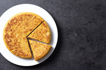 Traditional spanish omelette on black background. Top view. Copy space