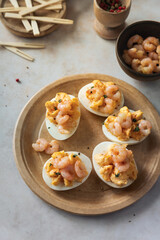 Deviled eggs with cooked shrimps stuffing on a plate, party food savory appetizer