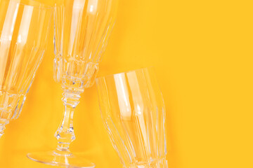 Empty crystal glasses on a yellow background. Place for your design.