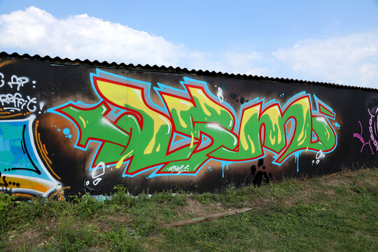 The old wall decorated with paint stains in the style of street art culture. Colorful background of full graffiti painting artwork with bright aerosol outlines on wall. Colored background texture