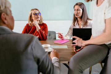 Office colleagues having casual discussion during meeting in conference room. Group of women sitting in conference room and talking.