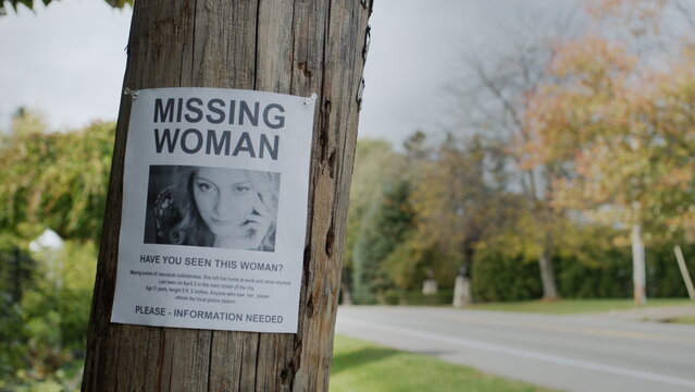 Poster for a missing young woman hangs on a pole near the road