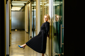 Obraz premium Portrait of blond businesswoman standing in office corridor, smiling.