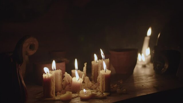 A lot of candles are burning on a wooden table 
