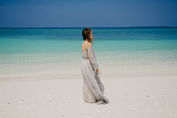 Fototapeta na wymiar woman walking on the beach in a beautiful dress