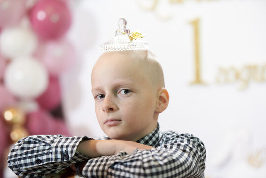 Bald boy 12 years old with a transparent crown on his head, at a party