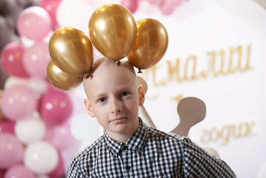 Bald boy 12 years old with a crown of balloons on his head, at a party