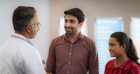 Indian Couple Visiting a Local City Hospital for a Health Check Up: Young Husband and Wife Talking...