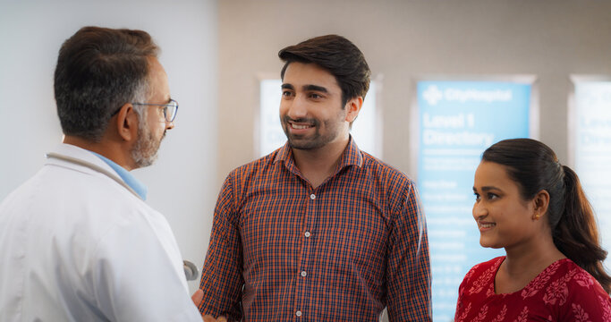 Indian Couple Visiting a Local City Hospital for a Health Check Up: Young Husband and Wife Talking to Their Doctor, Discussing Fertility Treatment Options