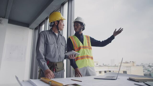 Low angle of foreman giving instructions to construction worker using tablet computer while planning work
