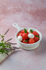 Watermelon Salad with mozzarella balls and mint on light rose background. healthy eating. Summer recipe concept