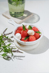 Watermelon Salad with mozzarella balls and mint on light rose background. healthy eating. Summer recipe concept
