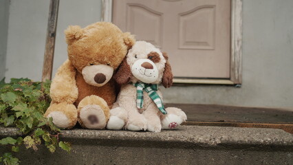 Two toys sit lonely on the threshold of an old house
