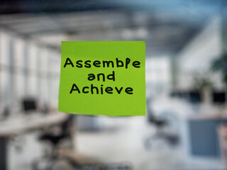 Post note on glass with 'Assemble and Achieve'.