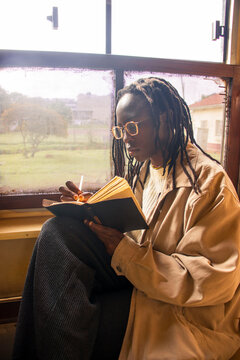 A young black woman journaling on a train