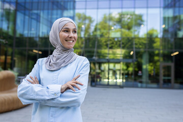 Portrait of a positive, successful Muslim businesswoman in a hijab, confidently smiling in an urban...