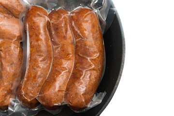 frozen sausage in a vacuum packing on top of cast iron skillet isolated on white background concept...