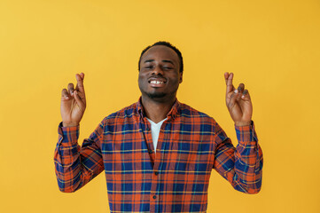Making hand gestures. Black man is in the studio against yellow background