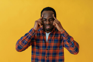 Thinking, fingers on the head. Black man is in the studio against yellow background