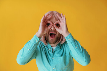 Making facial expression, hand gestures. Guy with pink hair is posing against yellow background