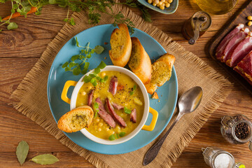 Traditional Polish pea soup. Prepared with smoked meat. Served in a yellow bowl with croutons. Home made.