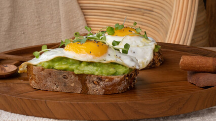 Sunnyside up egg on top of freshly smashed avocado sauce. Breakfast table with high nutritions vegan and vegetable food