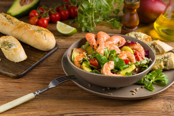 Spring salad with shrimp, mango and avocado. Served in a bowl, with croutons, sprinkled with roasted sunflower seeds.