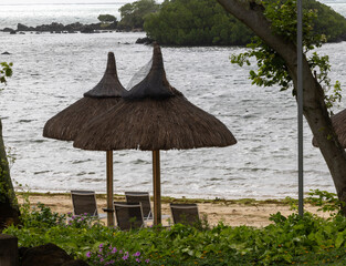 Sun umbrella and beach beds on tropical coastline, in Mauritius